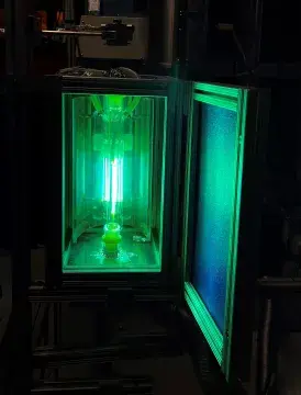 : A rectangular box has it’s door open revealing glowing green light filaments within.