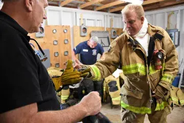 First responders in gear discuss an S&T prototype structure glove.