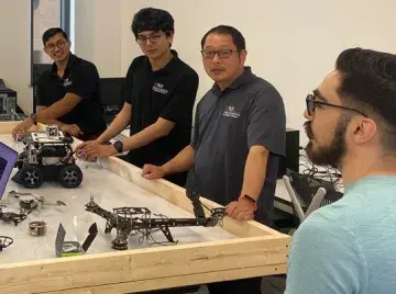 Dr. Qi Lu with team students in the robotics lab.