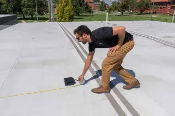 A man measuring part of a flat roof top.