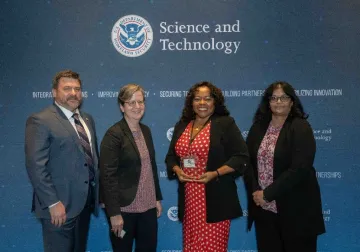 NAS-LIION co-owner Dr. Sharon Simmons (center, in red), was presented with the Judges Award at Converge 2023.She is joined here by (left to right) S&T Technology Transfer and Commercialization Branch representatives Ben Henry, Jenny Peters, and Branch Chief Kalpana Reddy.