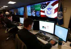Man looking at two computer screens at DHS Headquarters