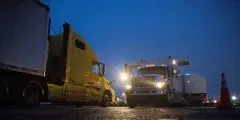 Two semi-trucks facing one another with headlights on