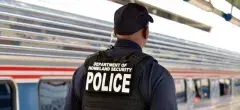 Department of Homeland Security Police walking next to an Amtrack train