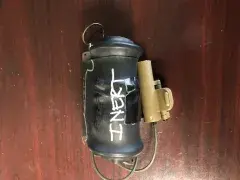 Shock Tube Dispenser device, a small black cylinder with a cap and some wiring.