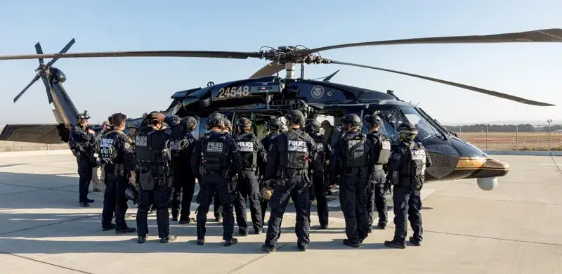 DHS officers in front of a CBP helicopter