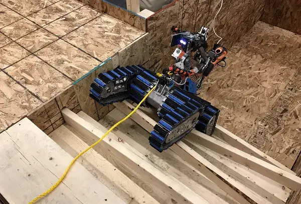 A robot trudges up a set of stairs, one of the test methods developed by S&T and NIST. Robot mobility was tested at three levels of difficulty, the height of which is said to be comparable to wall-climbing. 