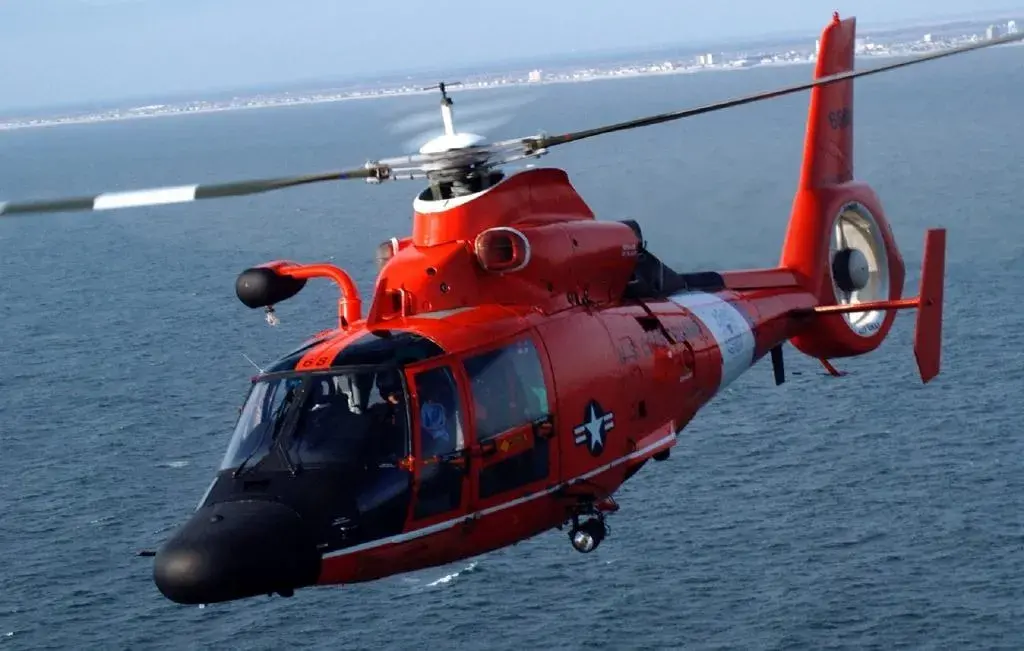 Coast Guard helicopter flying over water.
