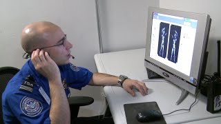 TSA officer at a computer monitor viewing a body scan image
